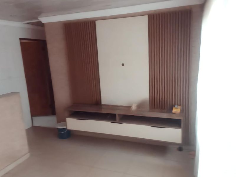 Living room featuring a modern built-in media console with decorative slatted wood wall paneling and neutral tiled flooring.