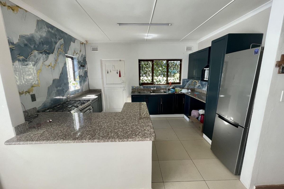 A functional kitchen featuring dark cabinetry, granite countertops, a gas stove, and decorative wall paneling, offering a practical layout with ample workspace.