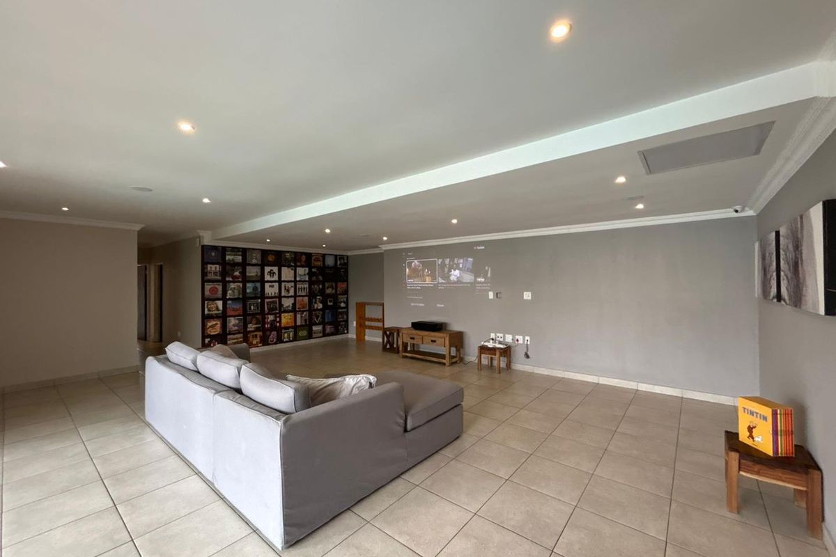 Spacious living area featuring recessed downlighting, tiled flooring, and a dedicated projection wall, ideal for a home cinema setup.