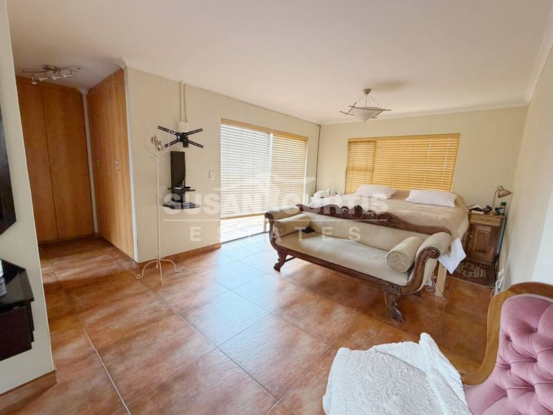 Spacious bedroom featuring tiled flooring, built-in cupboards, and large sliding doors providing natural light and access to the exterior.