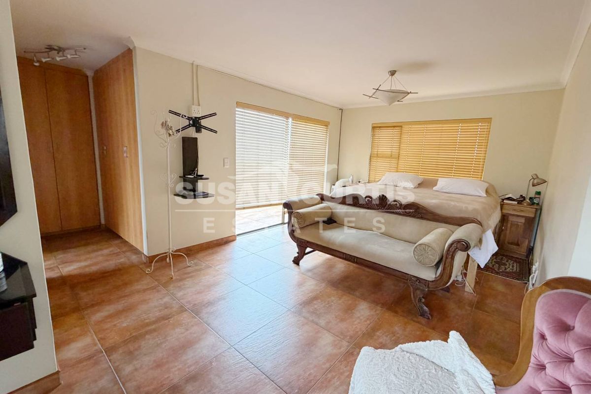 Spacious bedroom featuring tiled flooring, built-in cupboards, and large sliding doors providing natural light and access to the exterior.