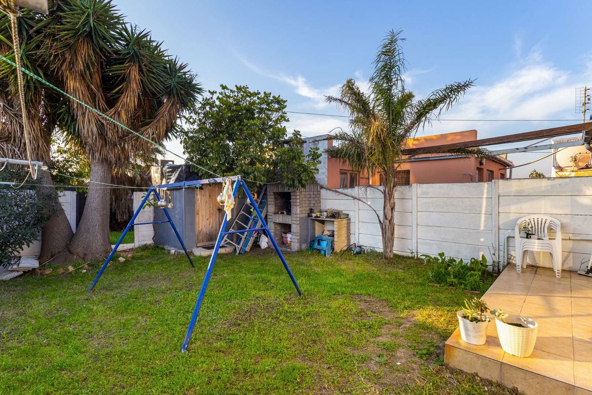 A rear garden area featuring a built-in brick braai, paved patio section, and perimeter walling, offering potential for outdoor landscaping and entertainment space.