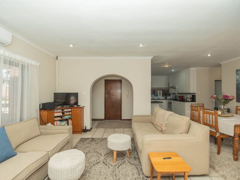 Open-plan living and dining area featuring tiled floors, recessed lighting, and an arched entryway leading to a functional kitchen space.