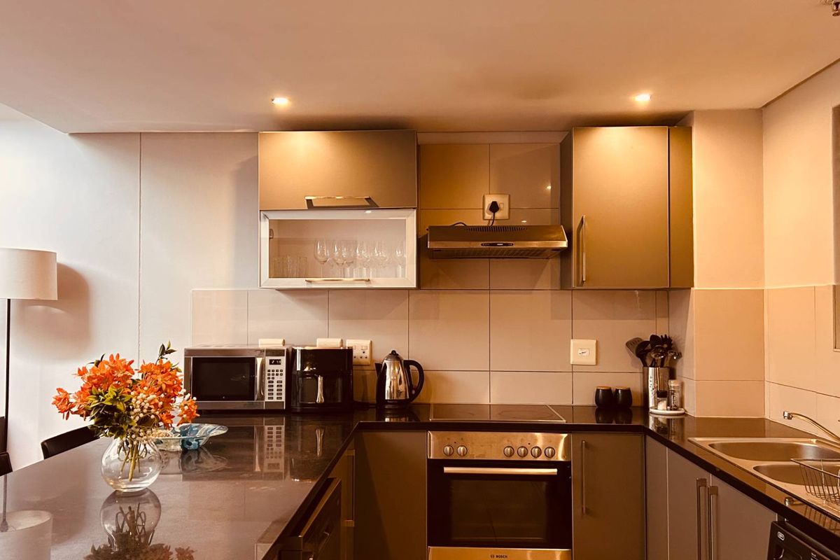 Modern kitchen featuring sleek cabinetry, stone countertops, integrated oven and hob, and a tiled backsplash with recessed lighting.