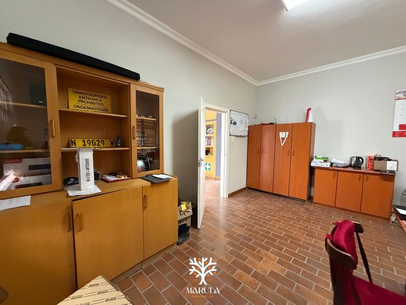 A functional office space featuring durable brick flooring, built-in storage cabinetry, and coved cornicing, providing a practical layout for business operations.