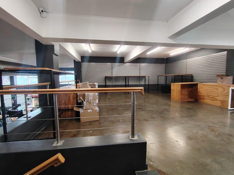 Spacious open-plan retail area featuring polished concrete floors, slatwall display panels, and modern industrial-style balustrades, suitable for various commercial business applications.