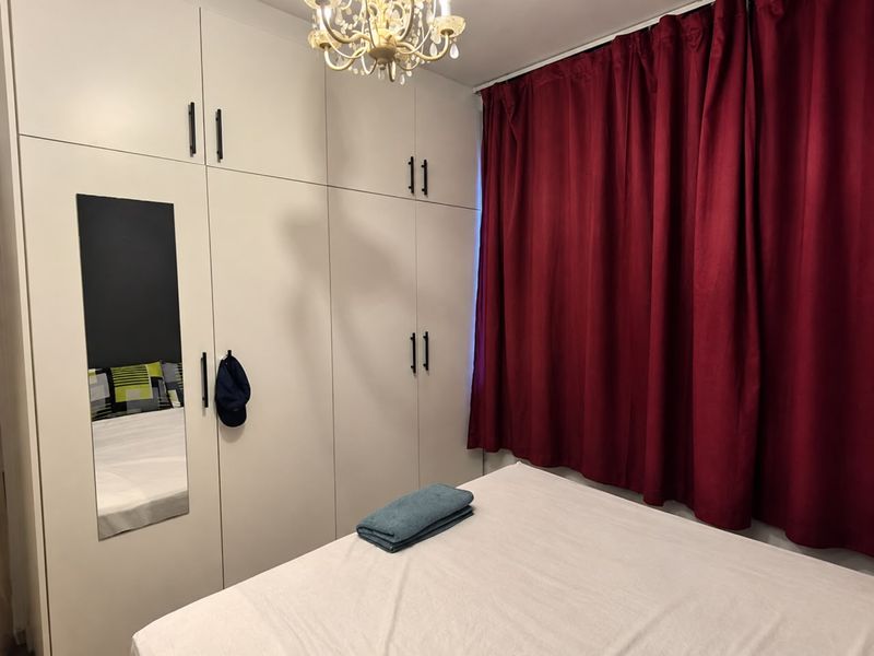 A bedroom featuring floor-to-ceiling built-in wardrobes with integrated mirror and neutral cabinetry, providing ample storage space.