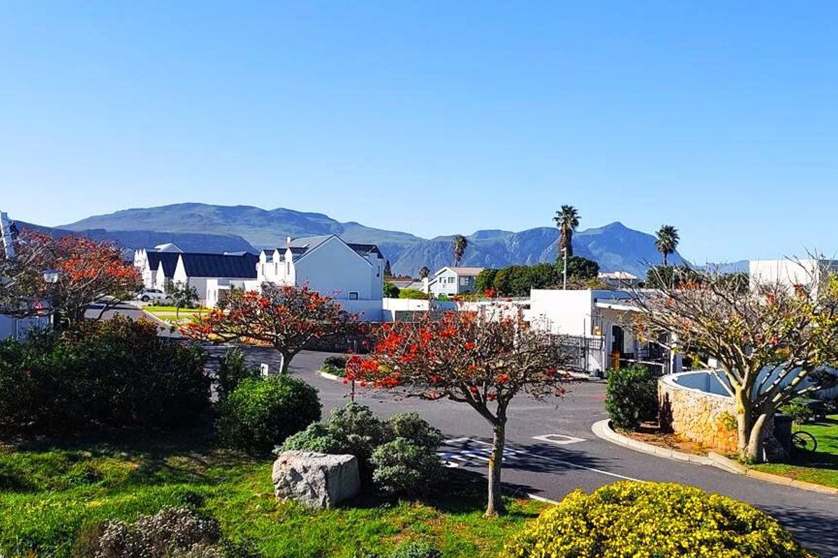 A scenic elevated view overlooking a residential estate with landscaped gardens, paved roads, and distant mountain vistas.