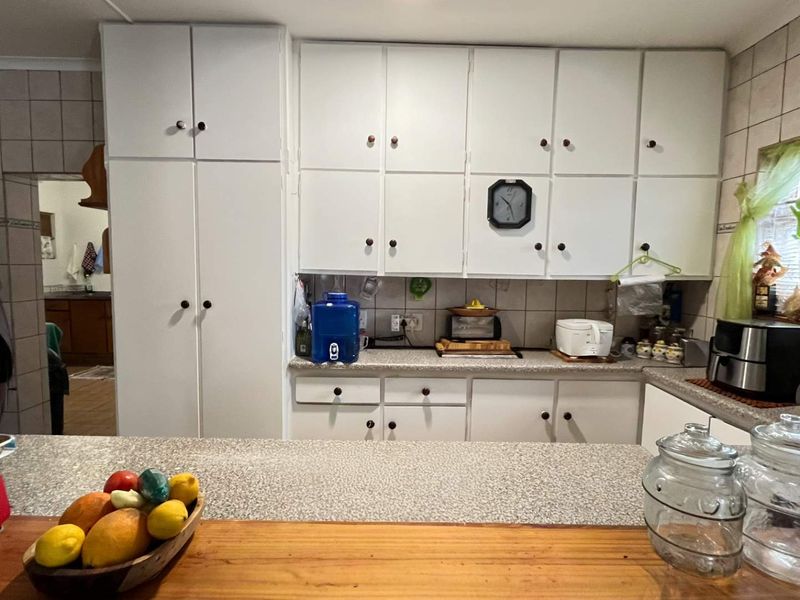 A functional kitchen featuring white built-in cabinetry, laminate countertops, and a tiled backsplash, offering a practical layout with ample storage space.