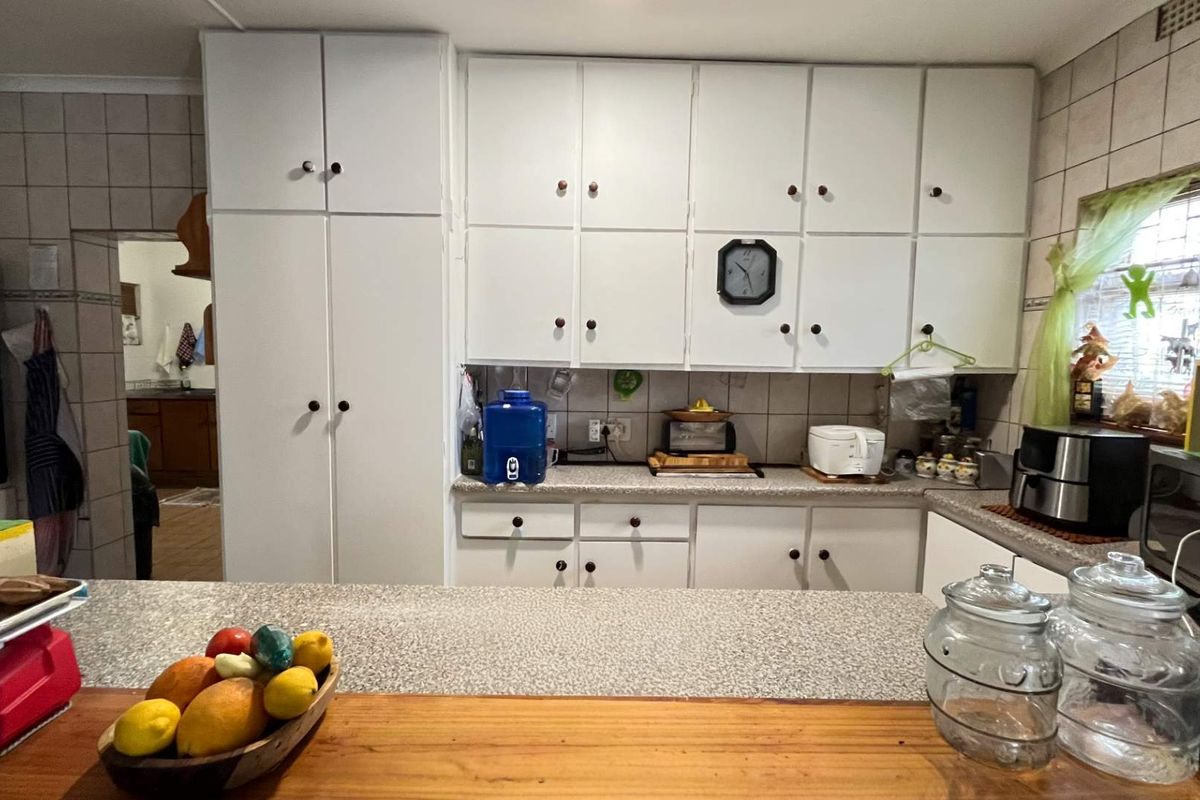 A functional kitchen featuring white built-in cabinetry, laminate countertops, and a tiled backsplash, offering a practical layout with ample storage space.