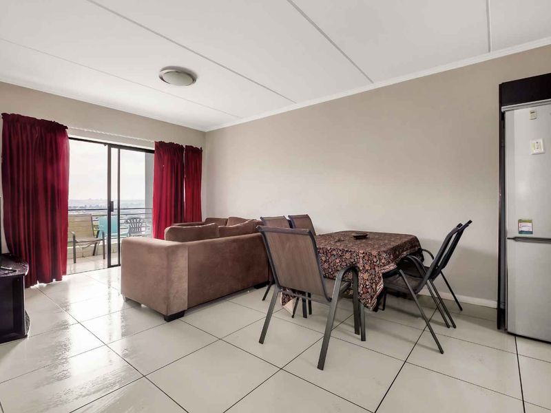 Open plan living and dining area featuring neutral wall tones, tiled flooring, and a sliding glass door providing access to the balcony.