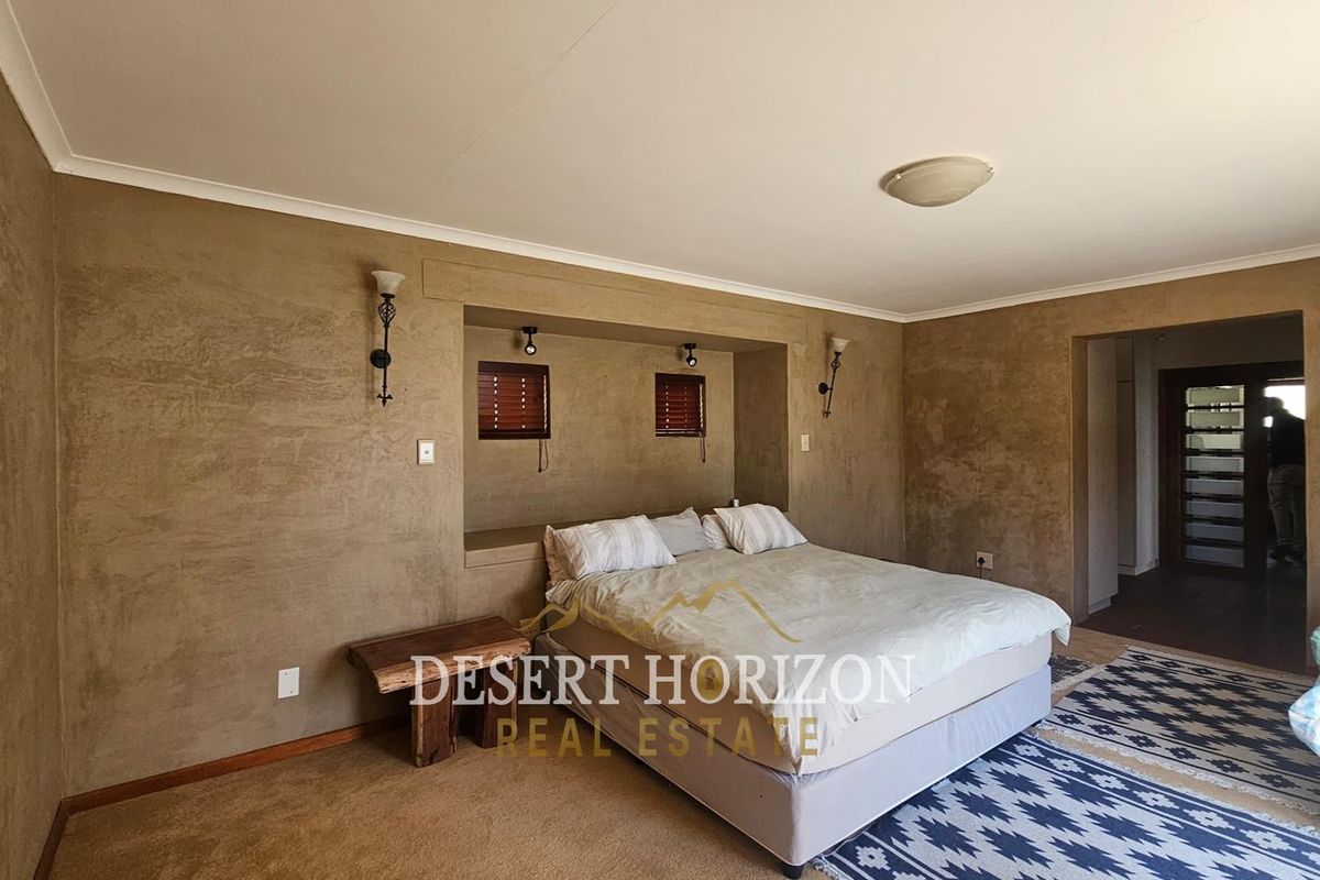 Spacious bedroom featuring a recessed bed alcove with integrated lighting, textured wall finishes, and neutral carpeting.