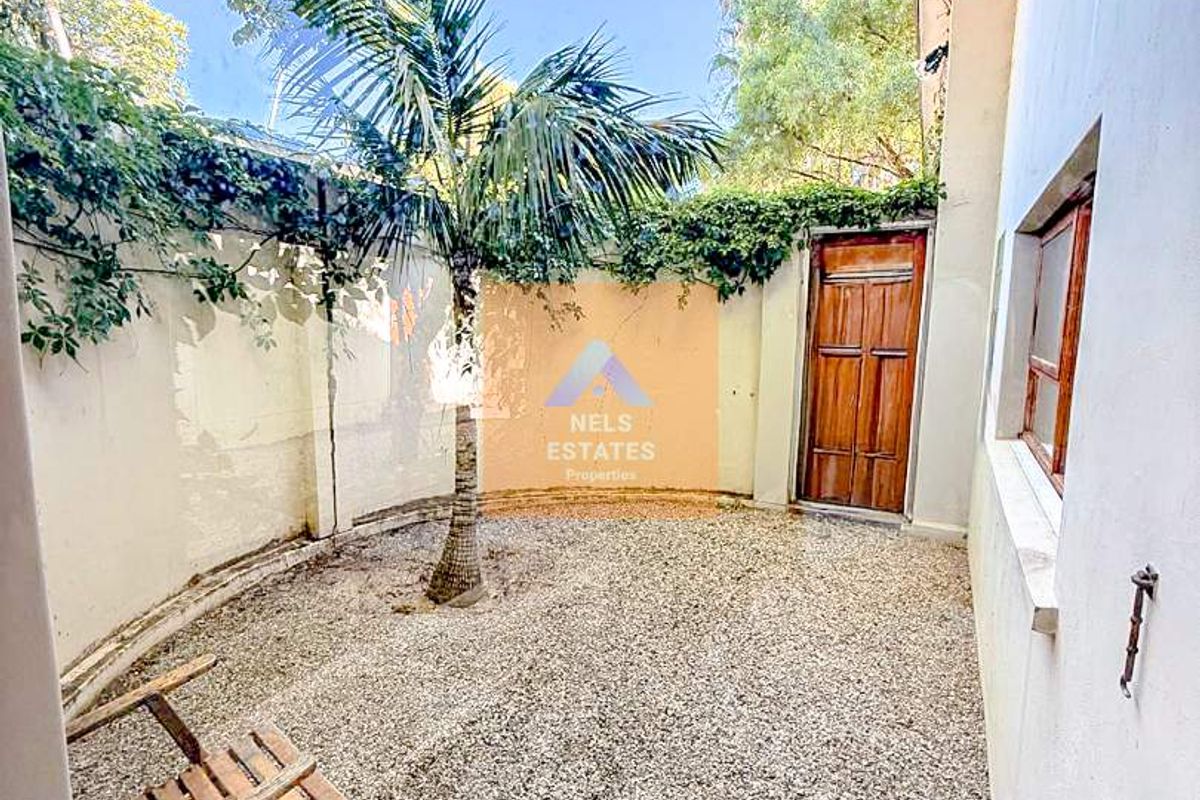 A private rear courtyard featuring a gravel surface, perimeter boundary walls, and a wooden access door.