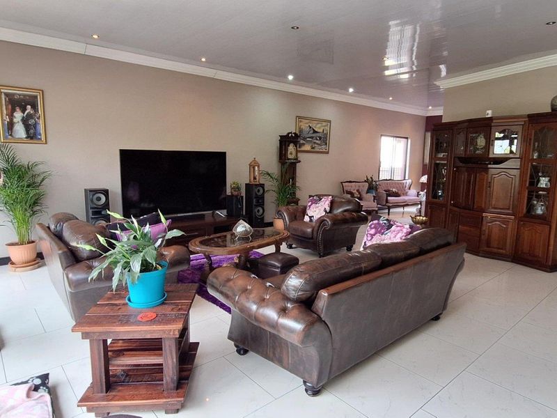 Spacious living room featuring large format floor tiles, recessed downlighting, and a high-gloss ceiling finish.