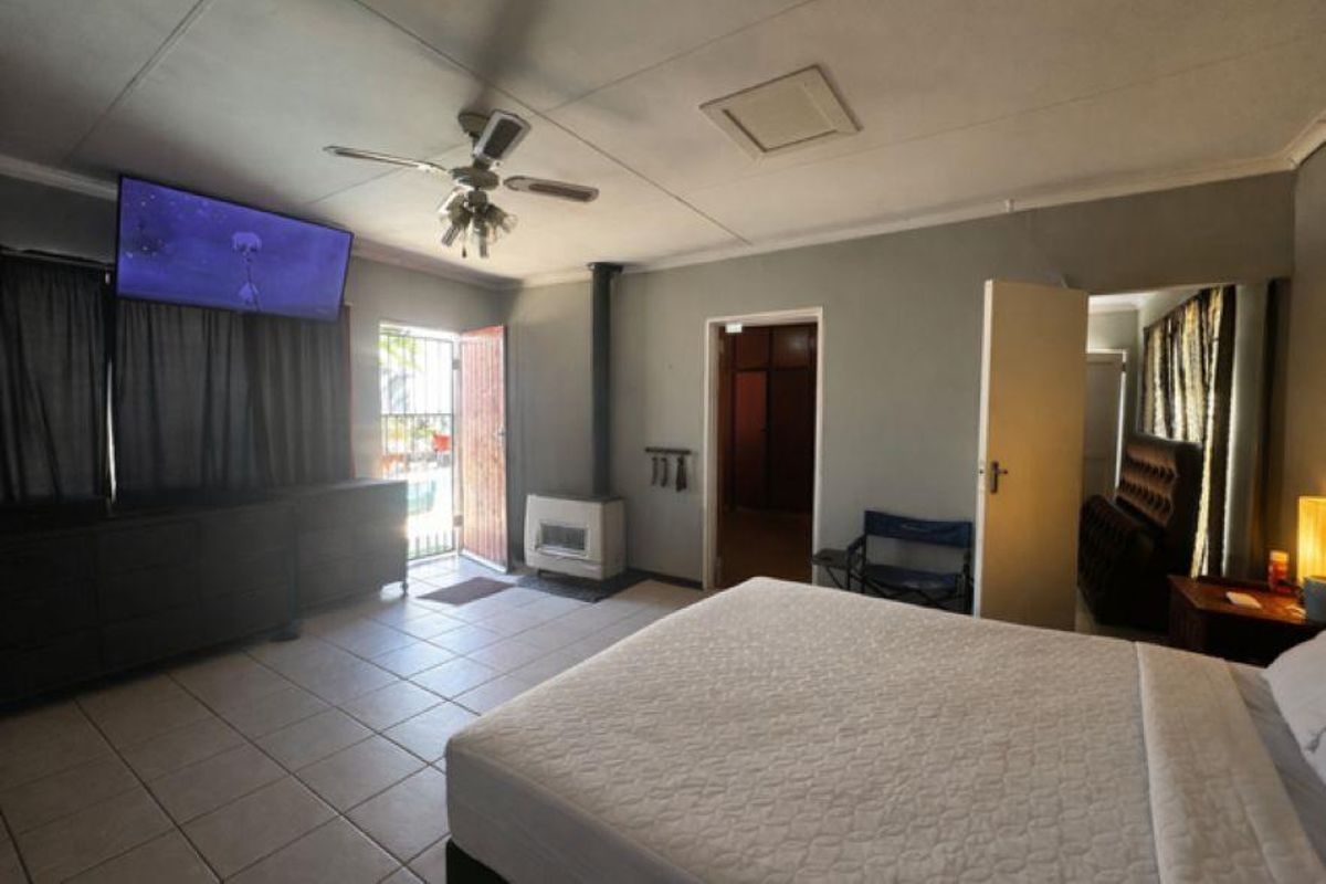 Spacious bedroom featuring tiled flooring, a built-in fireplace, ceiling fan, and direct access to an outdoor area.