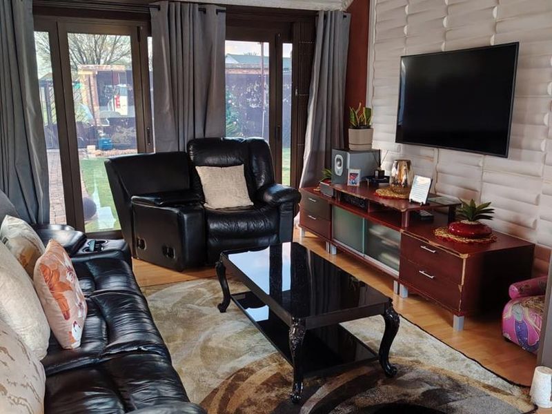 A living room featuring laminate flooring, a textured feature wall, and sliding glass doors providing access to the rear garden.