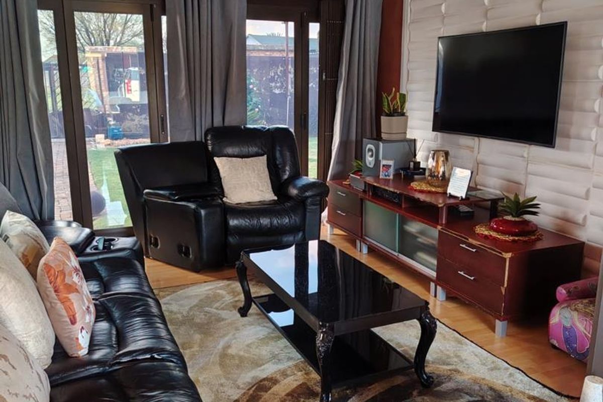 A living room featuring laminate flooring, a textured feature wall, and sliding glass doors providing access to the rear garden.