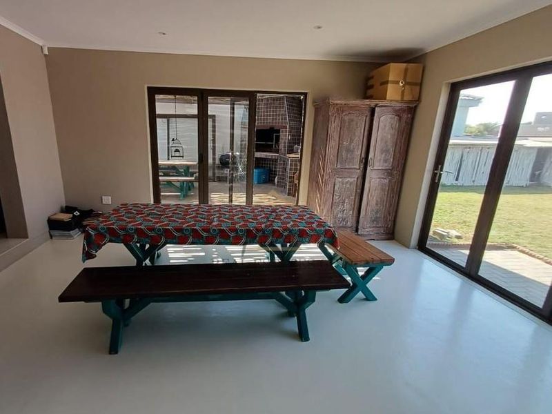 Spacious living area featuring smooth epoxy flooring, recessed lighting, and large sliding glass doors providing direct access to the outdoor patio and garden.