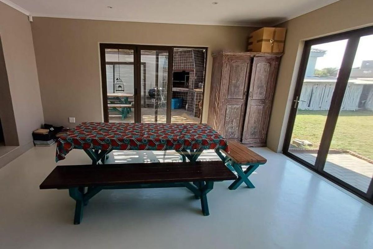 Spacious living area featuring smooth epoxy flooring, recessed lighting, and large sliding glass doors providing direct access to the outdoor patio and garden.