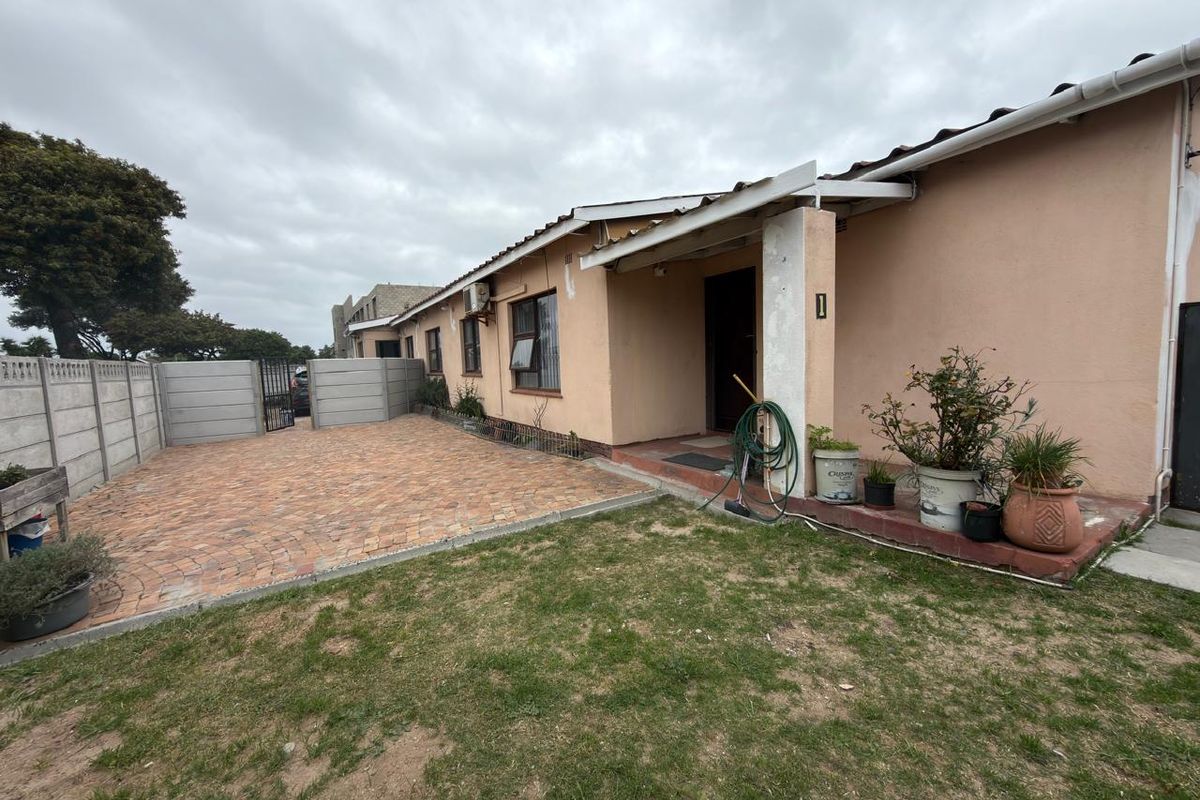 Rear exterior view of the townhouse featuring a paved patio area, precast boundary wall, and a small garden space.