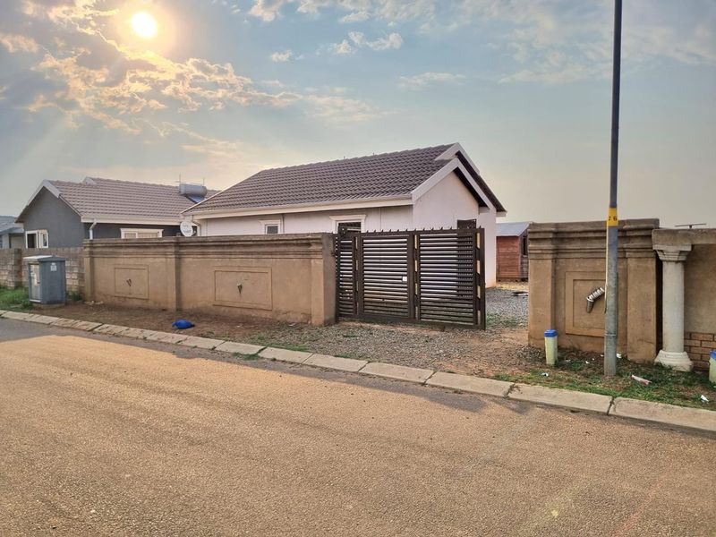 Front view of a residential property featuring a perimeter wall, metal gate, and tiled roof structure with a solar geyser.