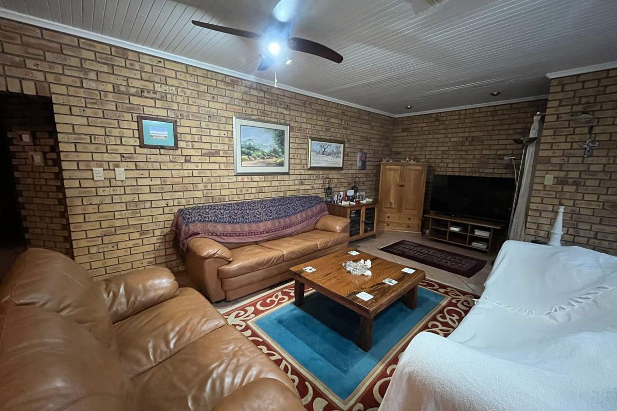 A living room featuring exposed face brick walls, a white timber-paneled ceiling, and a ceiling fan.