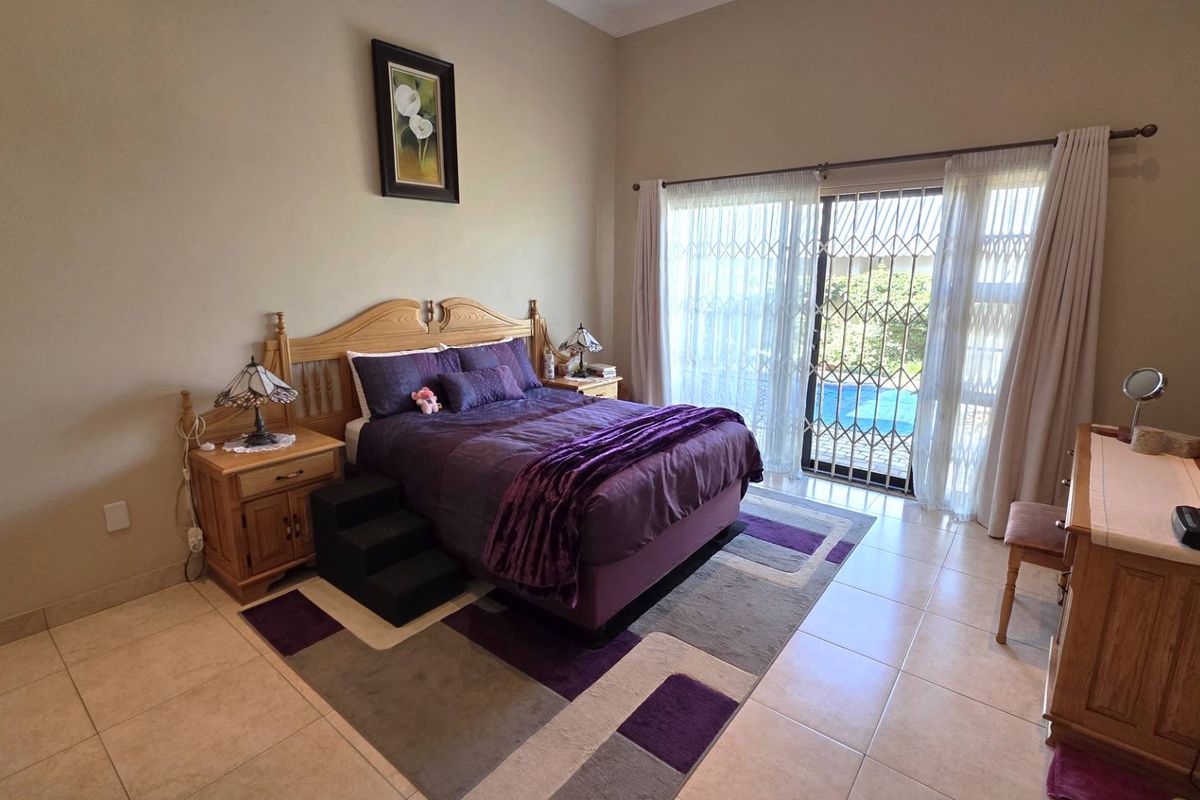 Spacious bedroom featuring tiled flooring, high ceilings, and sliding glass doors with security gates providing direct access to the pool area.