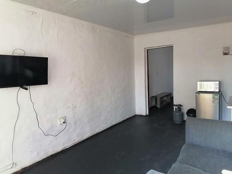 A simple living area featuring a glossy ceiling and textured walls, providing a functional space with potential for cosmetic updates.