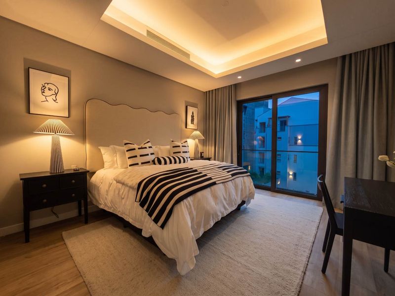 Modern bedroom featuring recessed ceiling lighting, ducted air conditioning, and large sliding glass doors leading to a balcony.