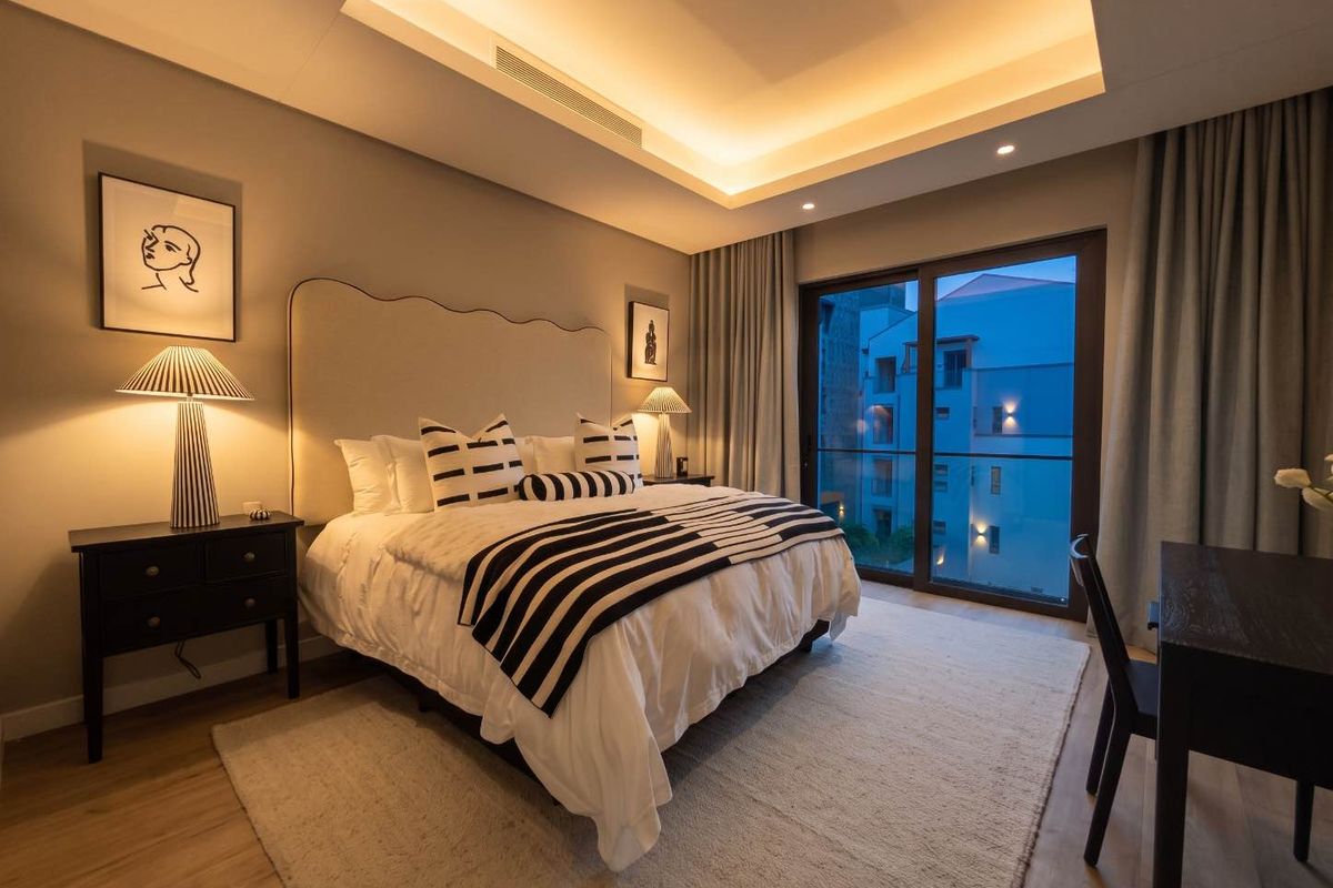 Modern bedroom featuring recessed ceiling lighting, ducted air conditioning, and large sliding glass doors leading to a balcony.