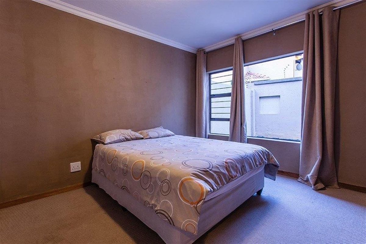 A bedroom featuring neutral wall tones, carpeted flooring, and a window with natural light.