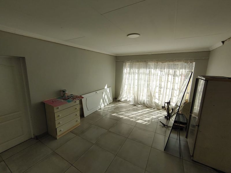 A living area featuring tiled flooring and ceiling cornice, currently requiring maintenance to the ceiling panels.