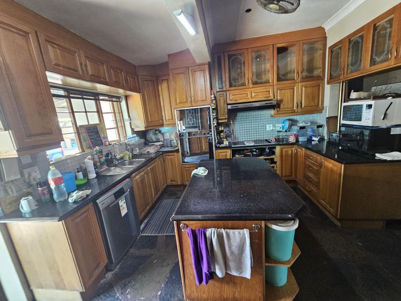A functional kitchen featuring extensive wooden cabinetry, granite countertops, a central island, and built-in appliances, offering a classic layout with ample storage space.