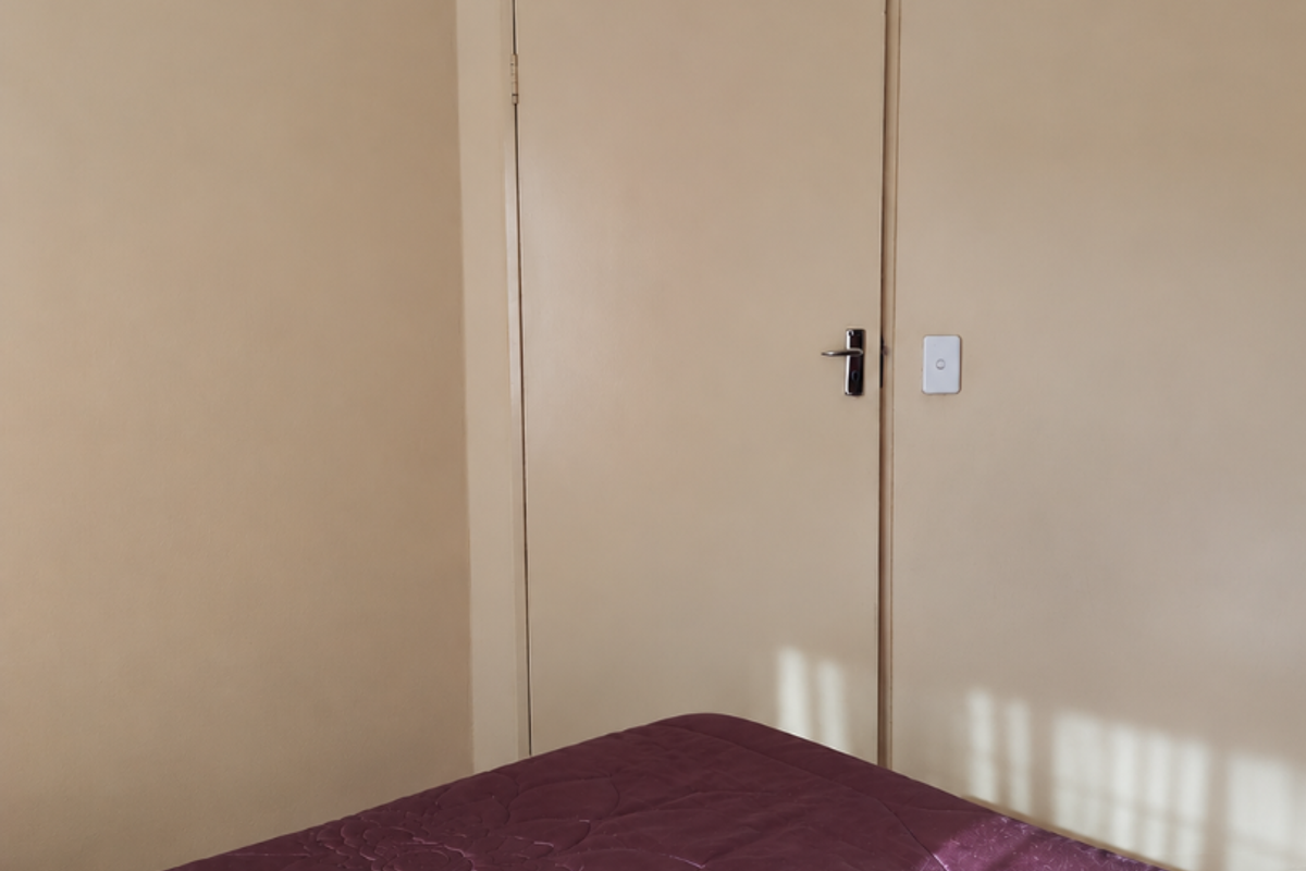 A simple bedroom interior featuring neutral wall paint, coving, and a standard internal door.