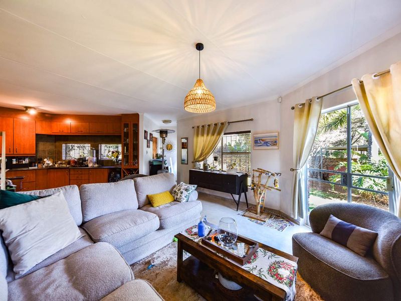Open-plan living area featuring a functional kitchen with wooden cabinetry and direct access to the garden through a sliding glass door.