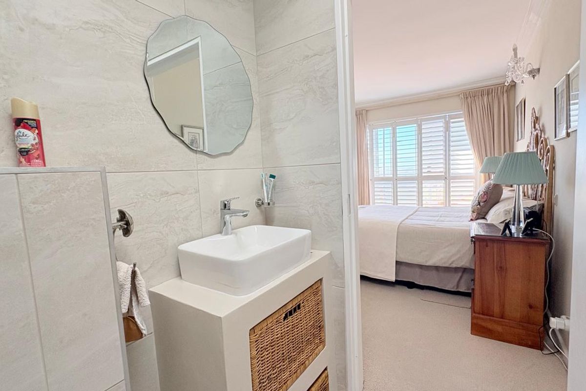 A modern bathroom featuring a vessel sink vanity and tiled walls, with a view into the adjacent bedroom.