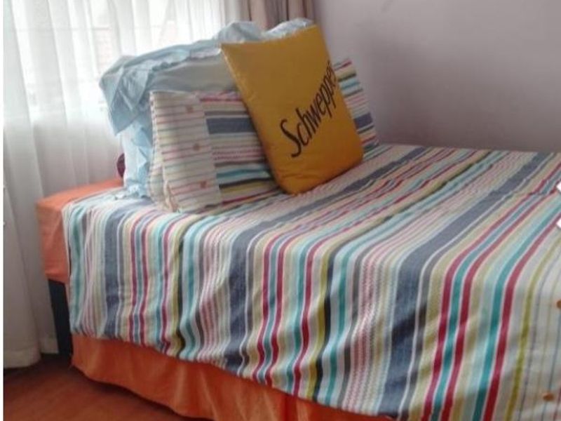 A bedroom featuring laminate flooring and window treatments, providing a functional space for rest.