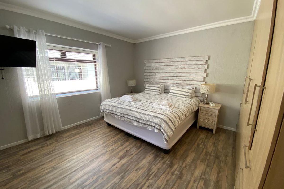 A well-maintained bedroom featuring wood-look laminate flooring, built-in cabinetry, and a large window providing natural light.