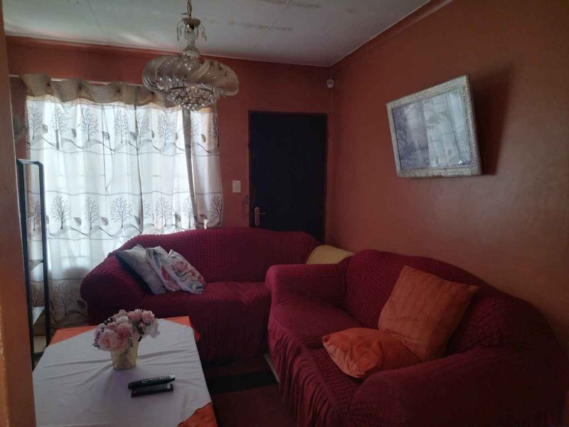 A living room space featuring a ceiling light fixture, currently showing signs of wear on the walls and ceiling.