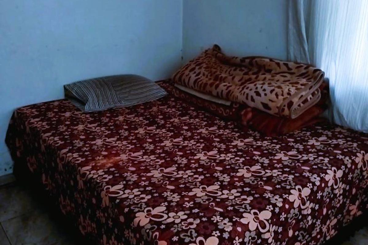 A bedroom featuring tiled flooring and plain walls, providing a functional space for rest.