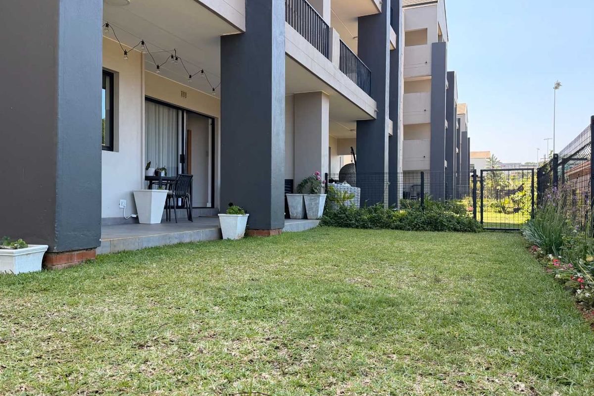 Ground floor apartment featuring a private covered patio and a well-maintained garden area enclosed by a metal fence.