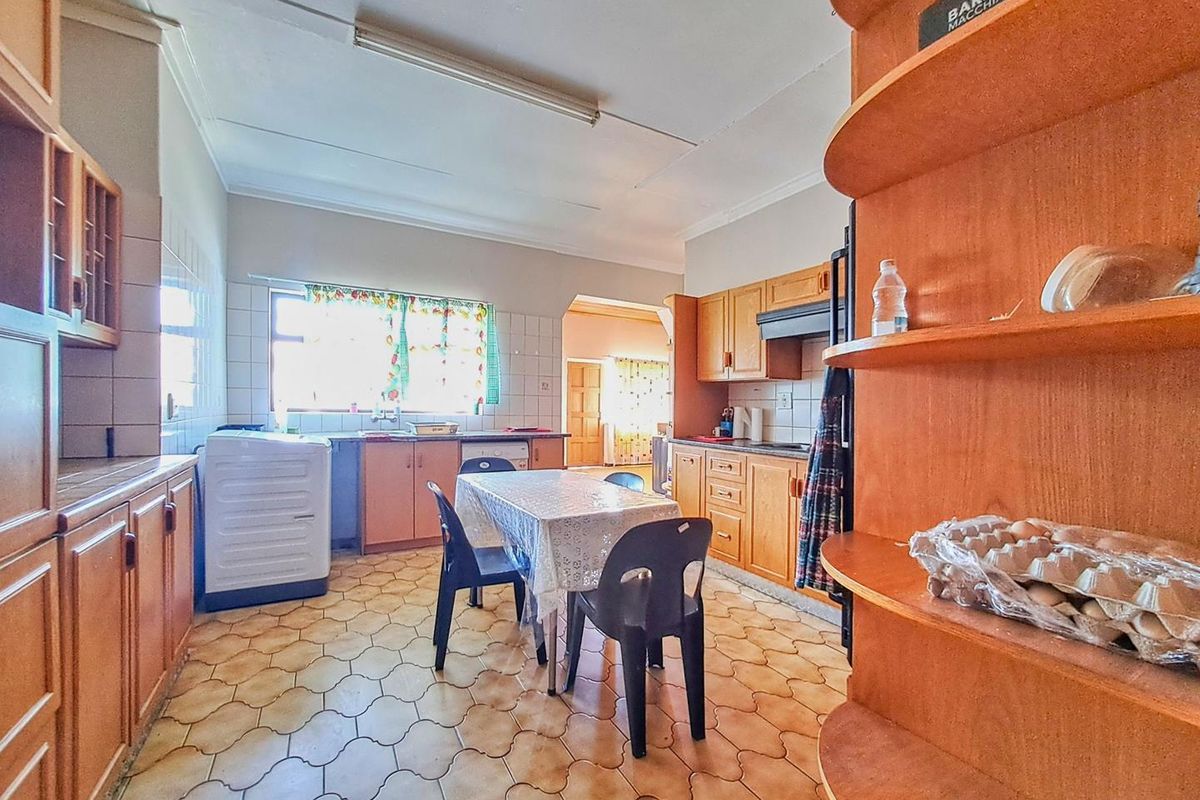A functional kitchen featuring wooden cabinetry, tiled flooring, and integrated workspace, offering a practical layout for daily meal preparation.