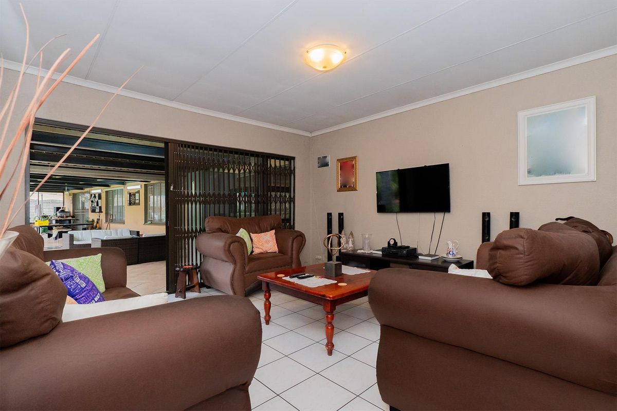 A comfortable living room featuring tiled flooring and a sliding security gate providing access to an outdoor patio area.