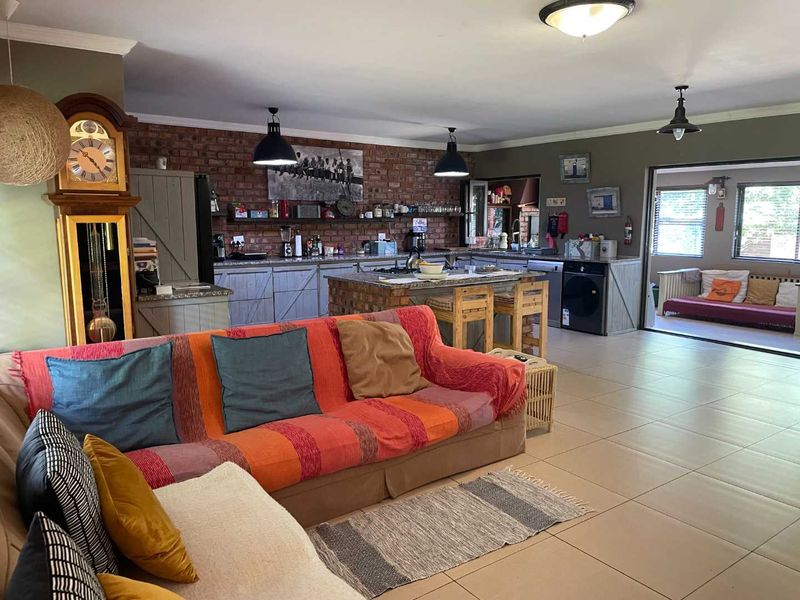 Spacious open-plan living and kitchen area featuring exposed brick walls, a central kitchen island, tiled flooring, and direct access to an adjoining patio space.
