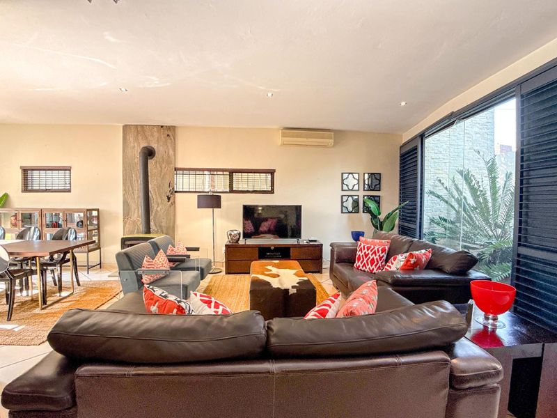 Spacious open-plan living area featuring tiled floors, a modern freestanding fireplace, and large sliding glass doors that provide ample natural light.