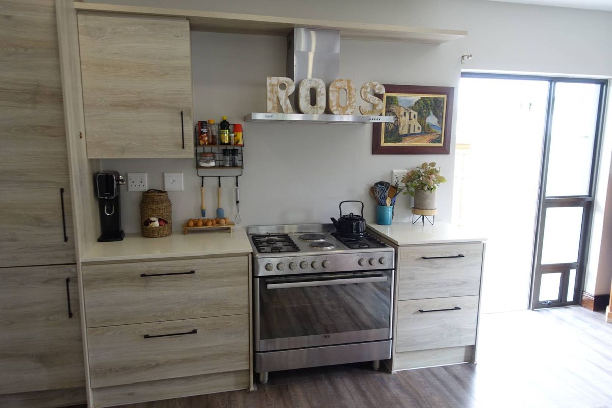 Modern kitchen featuring light wood-grain cabinetry, stainless steel gas stove with extractor fan, and durable laminate countertops.