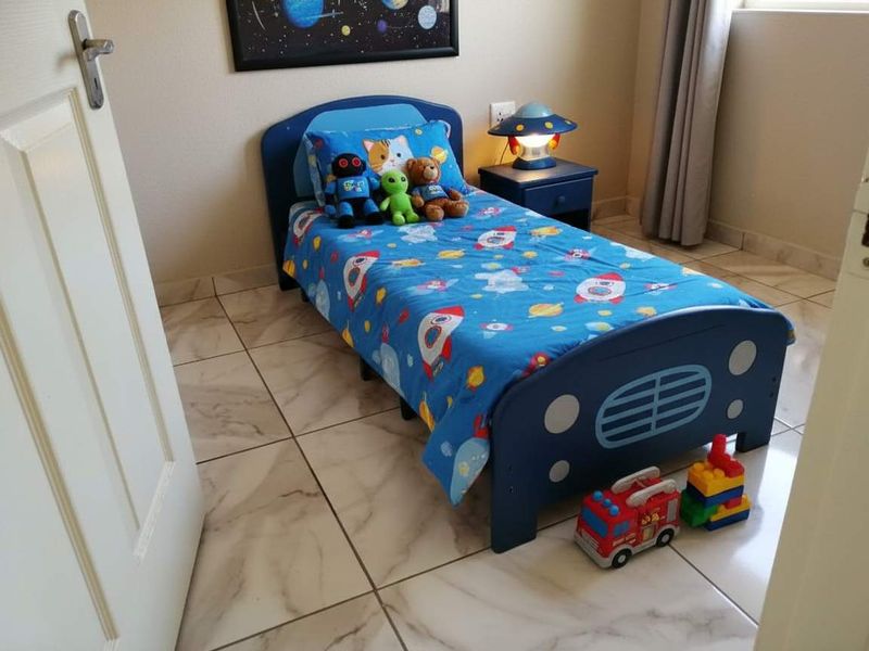 A compact bedroom featuring neutral wall tones and light-colored tiled flooring, providing a clean and functional space.