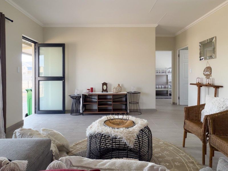 A bright and neutral living room featuring tiled flooring, coved ceilings, and a modern frosted glass door leading to the exterior.