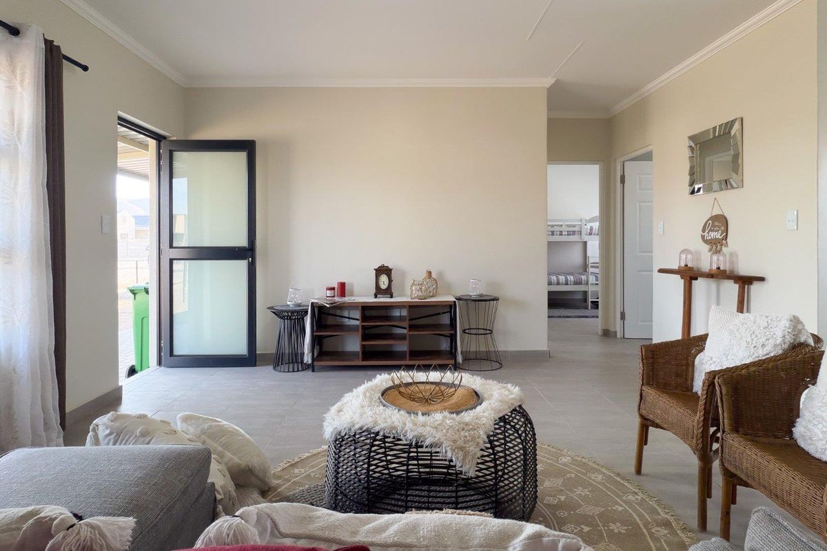 A bright and neutral living room featuring tiled flooring, coved ceilings, and a modern frosted glass door leading to the exterior.