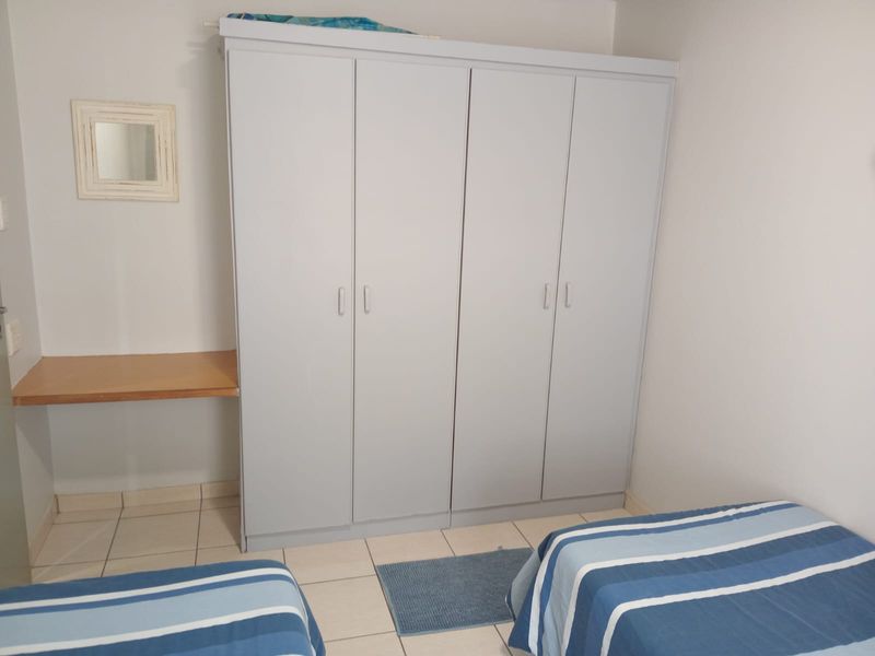 A bedroom featuring tiled flooring, a large built-in wardrobe, and a convenient built-in desk area.